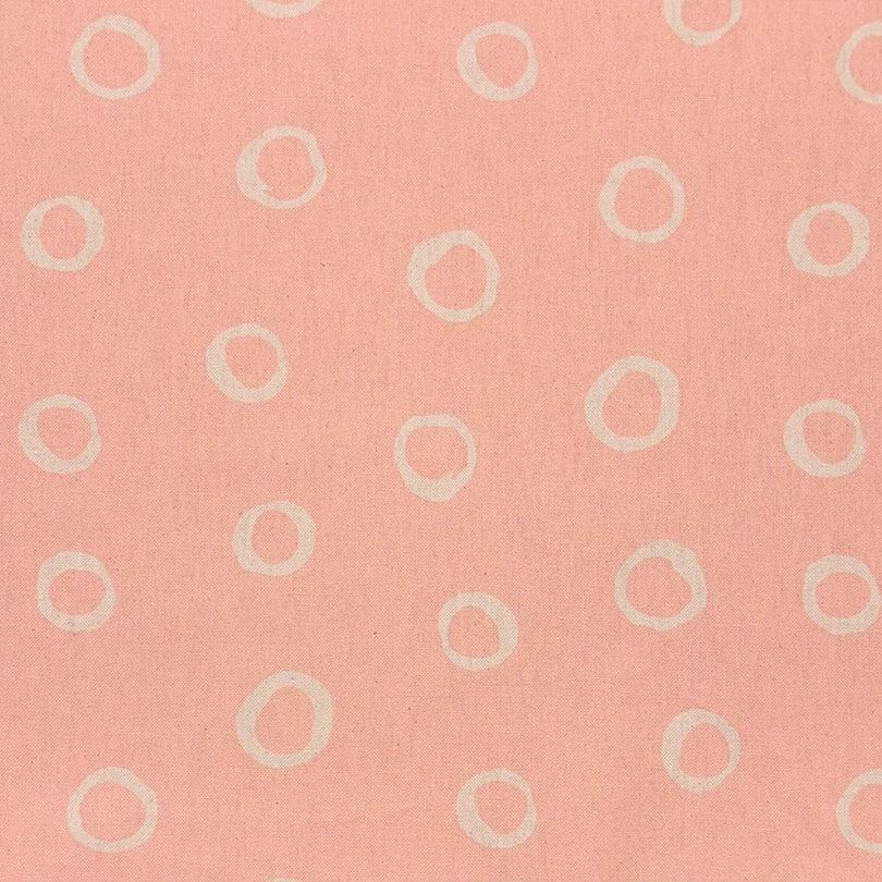 Blush spotted polka dot upholstery fabric with a soft pastel hue, perfect for adding warmth to furniture pieces.